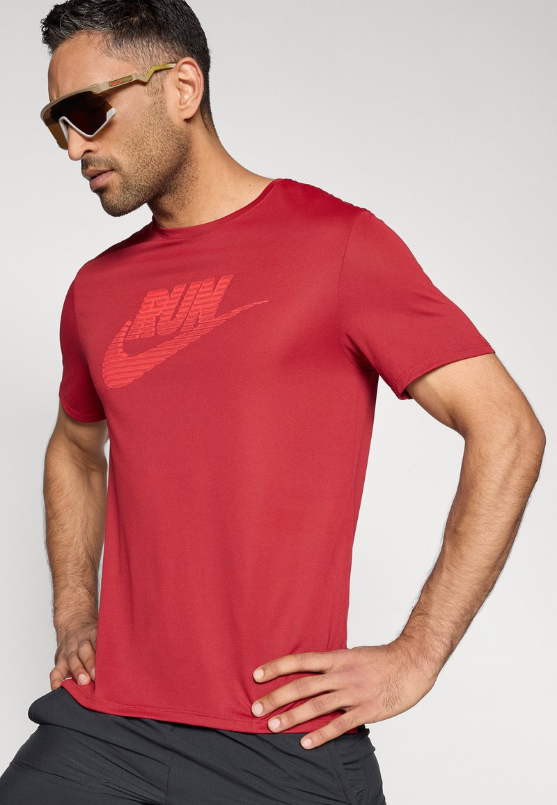 Rotes Sport-T-Shirt mit einem strukturierten Nike "RUN"-Logo. Hergestellt aus leichtem Stoff, mit kurzen Ärmeln und Rundhalsausschnitt.