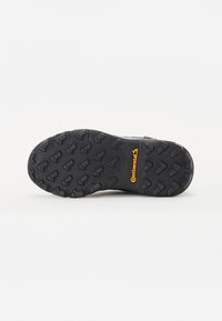 Black shoe sole with a distinct tread pattern and grooves for traction. Features "Continental" branding in yellow on the side.
