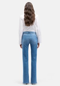 Jasnoniebieskie dzwony z dżinsu, z talią średniego wzrostu, dwoma tylnymi kieszeniami i czystym brzegiem bez przetarć.