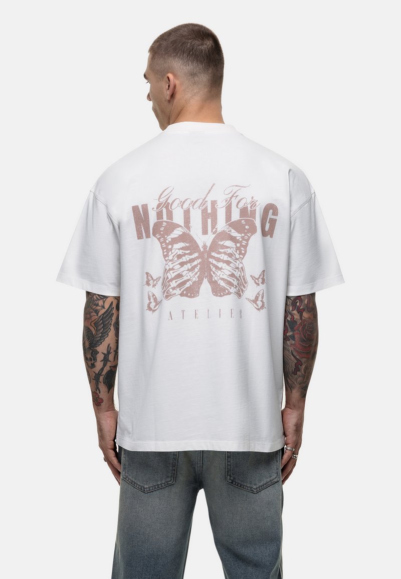 Witte katoenen T-shirt met een grote roze vlinderprint en tekst op de achterkant. Korte mouwen, relaxte pasvorm en minimalistisch ontwerp.