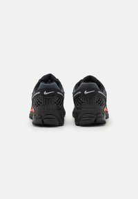 Nike running shoes in black with red accents, featuring a textured upper, mesh panels, and a cushioned sole for support and comfort.