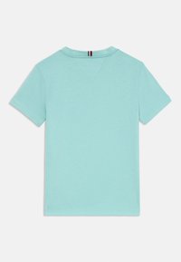 Svetlomodré bavlnené tričko s okrúhlym výstrihom, krátkymi rukávmi a malým červenobielym pruhovaným akcentom na zadnej strane výstrihu. Hladká textúra.