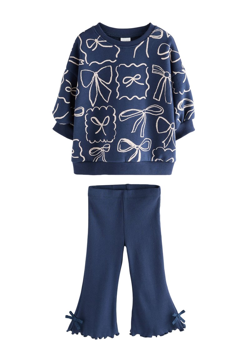 Sweat-shirt en coton bleu marine avec motifs de nœuds blancs et poignets côtelés, assorti à un pantalon évasé côtelé avec accents de nœuds aux ourlets.