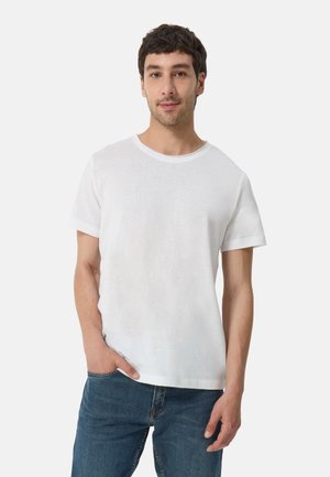Weißes T-Shirt mit kurzen Ärmeln und rundem Hals, aus weichem Stoff, kombiniert mit blauen Jeans. Einfaches, lässiges Design ohne Muster.