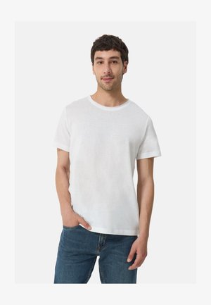 White short-sleeve t-shirt with a round neck, made of soft fabric, paired with blue denim jeans. Simple, casual design with no patterns.