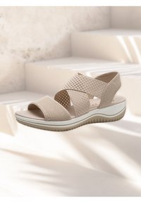 Sandalo beige con cinturini in elastico a incrocio, punta aperta, tomaia in rete traspirante, soletta imbottita e suola in gomma texturizzata.