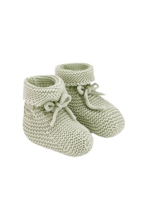 Chaussons de bébé tricotés doux vert clair avec revers pliés et nœuds attachés sur fond blanc.