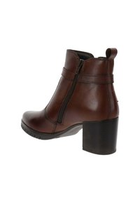 Bottine en cuir marron, avec un bout rond, une fermeture éclair sur le côté et un talon carré. Présente des accents de couture et une languette à l'arrière.