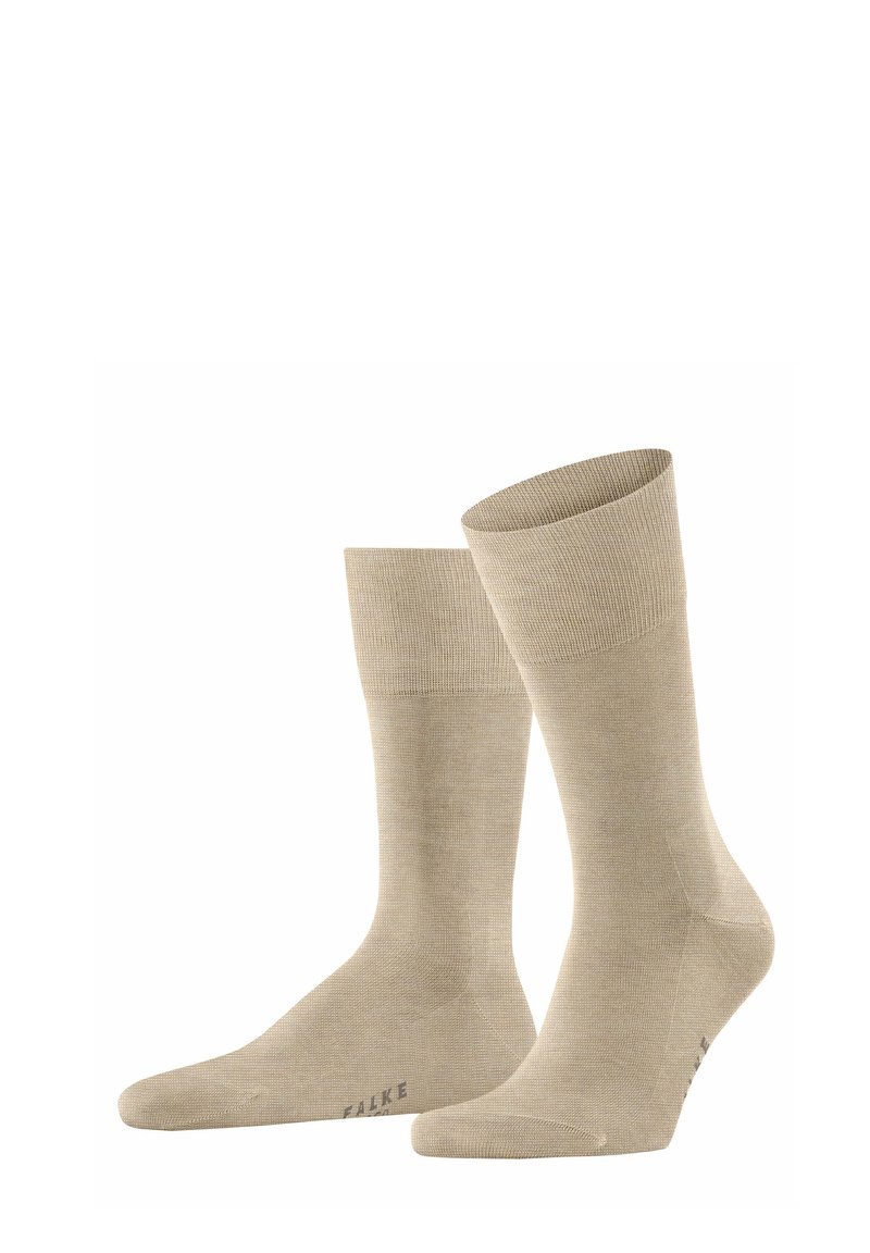 Beżowe skarpetki bawełniane z prążkowaną teksturą, długość do połowy łydki, z wzmocnionym palcem. Nazwa marki "FALKE" nadrukowana na podeszwie.
