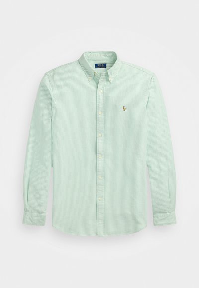 Ανοιχτό πράσινο πουκαμίσα με ρίγες, μακριά μανίκια, γιακά με κουμπιά και μικρό κεντητό λογότυπο στην αριστερή πλευρά.