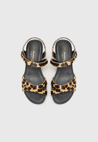 Sandales imprimées léopard avec deux brides croisées, accents noirs et semelle intérieure lisse noire. Présente un détail de quincaillerie décoratif.
