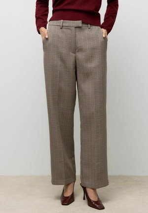 Un pantalon à carreaux taille haute en marron, présentant une coupe large, des poches latérales et une texture lisse; associé à des talons bordeaux.