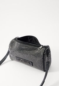 Svart handväska med silvernitar, dragkedjestängning och avtagbar axelrem. Har ett namnskylt präglat med "LOVE MOSCHINO."