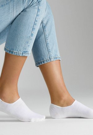 Weiße Baumwoll-Socken in Knöchelhöhe werden an den Füßen eines Models präsentiert. Die Socken haben eine glatte Textur und ein niedrig geschnittenes Design, das teilweise die Haut sichtbar macht.