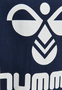 Tela azul marino con un gran diseño gráfico blanco que presenta una forma simétrica similar a una abeja y patrones geométricos debajo.