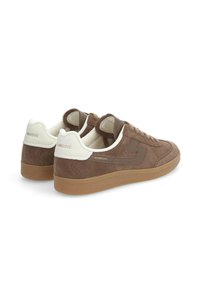 Baskets en suédine marron avec un talon blanc et un design à lacets. Possède une semelle en gomme texturée et un logo subtil sur le côté.