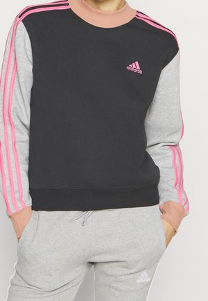 Sudadera negra y gris con logo de Adidas en rosa, cuello acanalado y rayas rosas en las mangas, hecha de un material de algodón mezclado y suave.
