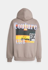 Světle hnědá mikina s kapucí s velkým grafickým motivem, na kterém je západ slunce a siluety labutí. Text zní "Couture Club" v bílé a modré barvě.