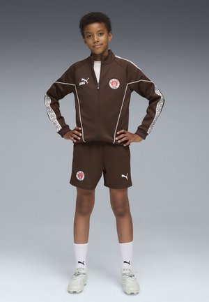 Ensemble de sport marron avec veste zippée et shorts. Accents et logo blancs sur la poitrine. Chaussettes et chaussures en blanc et gris clair.