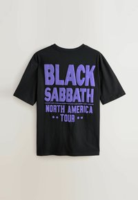 Sort t-shirt med stor lilla tekst, der står "BLACK SABBATH NORTH AMERICA TOUR" på ryggen, vist på en neutral baggrund.