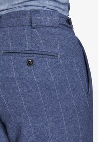 Pantaloni in lana blu con finitura testurizzata, motivo a righe sottili e tasca posteriore con chiusura a bottone nero.