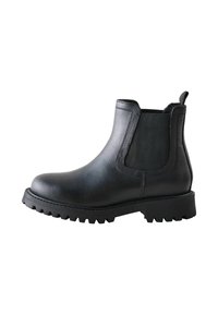 Bota Chelsea de cuero negra con paneles laterales elásticos y suela resistente, vista desde un lado. Cuenta con una lengüeta para facilitar su puesta.