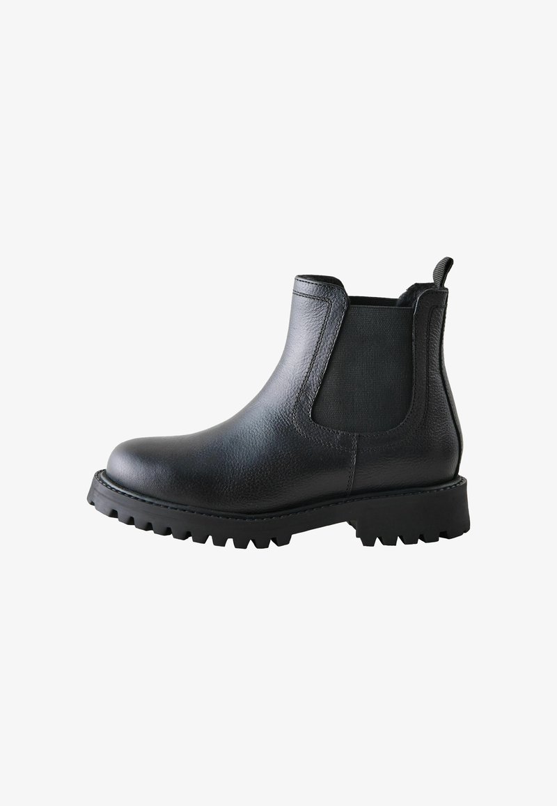 Bottine en cuir noir avec semelle crantée épaisse, panneau latéral élastique et languette à l’arrière pour un enfilage facile.
