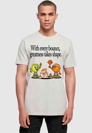 Helles graues T-Shirt mit bunten Cartoon-Bällen (Baseball, Basketball) und dem Text: "Mit jedem Sprung nimmt Großartigkeit Gestalt an."