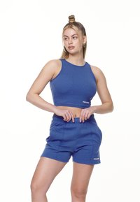 Blå kort topp og matchende shorts, laget av mykt stoff, med ribbet tekstur og subtil logo detalj på shortsen. Avslappet passform.