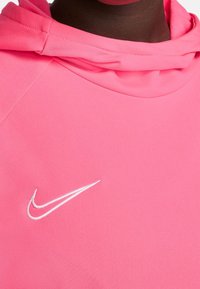 Sudadera rosa con una textura suave, una capucha ajustada y un logo de Nike bordado en blanco en el área del pecho izquierdo.