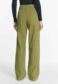 Olijfgroene cargobroek met wijde pijpen en een ontspannen pasvorm, voorzien van meerdere zakken en gestikte details. Gemaakt van duurzaam materiaal.
