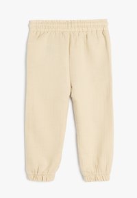 Beige, elastiske bukser med taljeelastik lavet af tekstureret stof. Har samlede mansjetter og et let, åndbart design. Klassisk afslappet pasform.