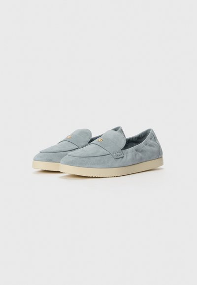 Mocassini in suede azzurro chiaro con punta arrotondata, dettagli cuciti, suola in gomma e sottile emblema dorato sulla parte anteriore. Design confortevole.