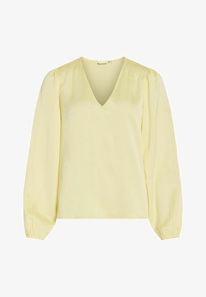 Blouse jaune avec un col en V, des manches longues bouffantes et des détails smockés aux épaules. Réalisée en tissu lisse et léger.