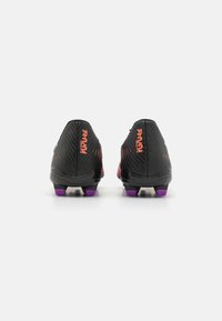 Sorte fodboldstøvler med tekstureret overdel, lilla studs og orange logo-detalje bagpå. Har en strømlinet design og letvægtskonstruktion.