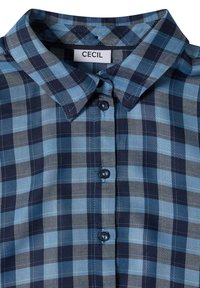 Chemise à carreaux bleue et noire avec boutons, col et étiquette blanche portant la mention "CECIL" à l'intérieur du col.