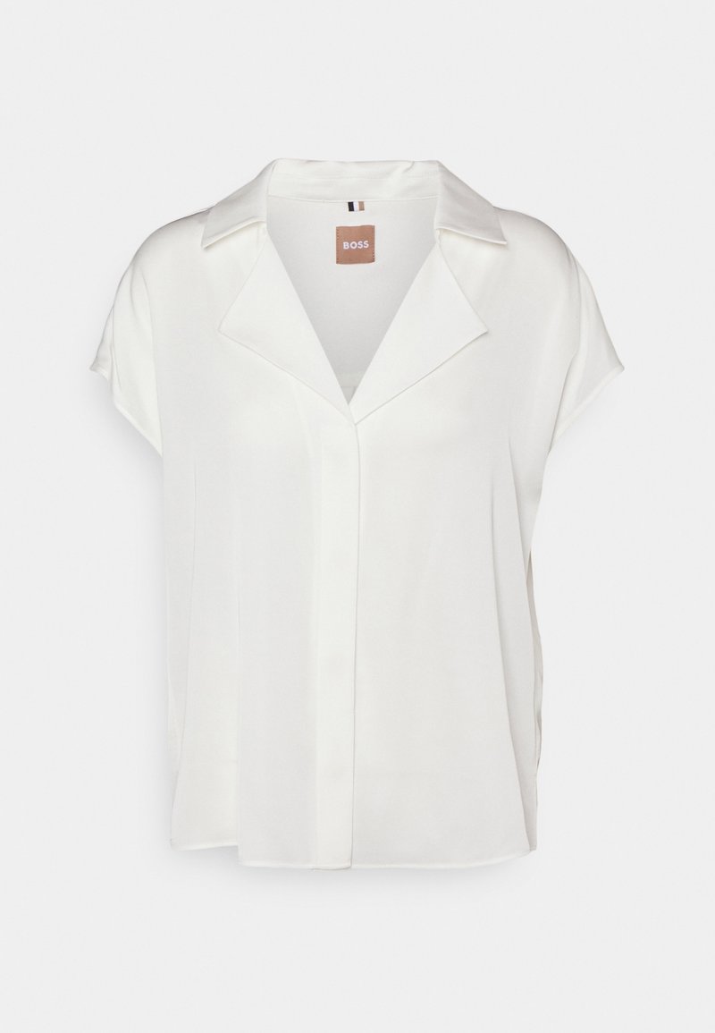 Blouse blanche à manches courtes avec col ouvert et coupe ample, présentant une patte de boutonnage centrale cachée et une étiquette BOSS à l'intérieur de l'encolure.