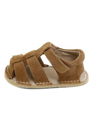 Sandalia para niño pequeño de ante marrón con puntera abierta, correa de velcro y suela beige cosida, mostrada de lado sobre un fondo blanco.