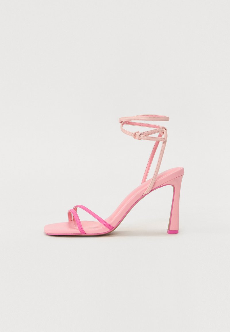 Sandal con tacco alto rosa con due cinturini sottili sulla punta, una cinghia pronunciata alla caviglia e un design con punta quadrata. Il tacco è elegante e affusolato.