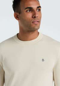 Crème, geribbelde trui met ronde hals gemaakt van een zacht materiaal, met een klein navy logo op de linkerkant van de borst en een getailleerde pasvorm.