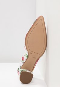 Chaussure à bout pointu à motif floral avec semelle marron clair et talon bloc, vue de dessous sur fond blanc.