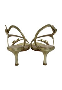 Sandali alti con tacco a stiletto dorati e finitura texturizzata, con un tacco sottile e un accentuato fibbia sulla cinghia alla caviglia.