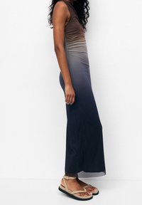 Mouwloze maxi-jurk met een ombre-design dat overgaat van bruin naar donkerblauw, gemaakt van een gladde stof. Sandalen met een strappy ontwerp.