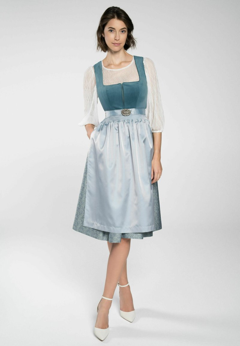 Traditionelles Kleid mit einem blauen Samtoberteil, weißen Spitzeärmeln und einem hellblauen Satinkleid mit einem dekorativen Silbergürtel.