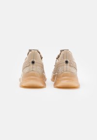 Beige sneakers with a mesh upper and decorative rhinestones, featuring a cushioned sole and textured back for enhanced support.