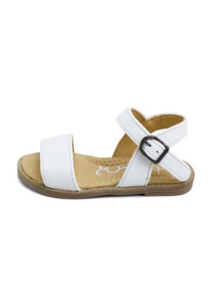 Sandalia blanca con puntera abierta, correa en el tobillo, hebilla negra, plantilla acolchada beige y suela plana color beige.