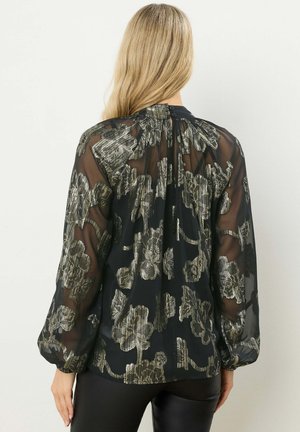 Schwarze transparente Bluse mit metallic floralem Muster, langen puffärmeligen Ärmeln und Knopfverschluss am Hals. Glatte Textur, fließendes Design.