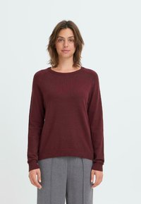Burgundowy sweter dzianinowy z okrągłym dekoltem, długimi rękawami i prążkowanymi zakończeniami. Wykonany z miękkiego materiału, o gładkiej fakturze i minimalnych detalach.