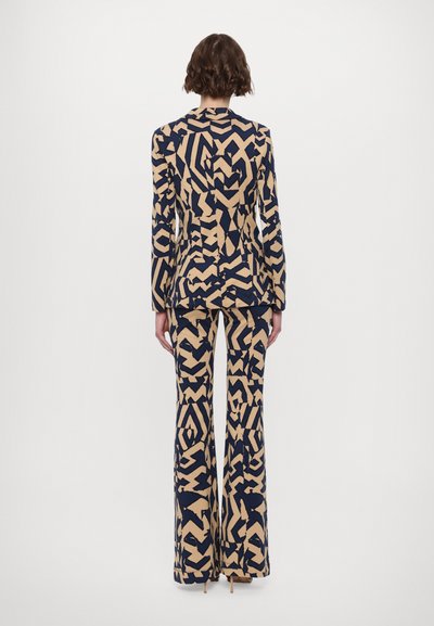 Navy and beige patterned suit featuring a fitted blazer with long sleeves and wide-leg pants, showcasing an abstract graphic design.