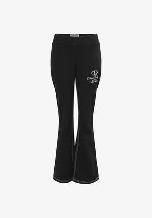 Black flared pants with white contrast stitching and a small white True Religion logo on the upper front thigh.